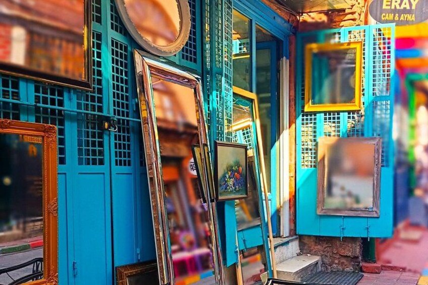 A storefront with various framed pictures and mirrors displayed outside. 2