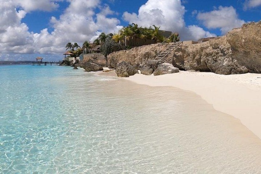Ein Strand mit klarem türkisblauem Wasser, weißem Sand und einem Felsen mit Palmen. 3