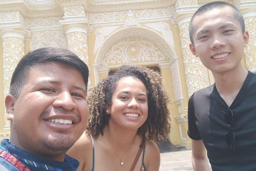 Three people standing in front of a building with ornate architectural details. 2