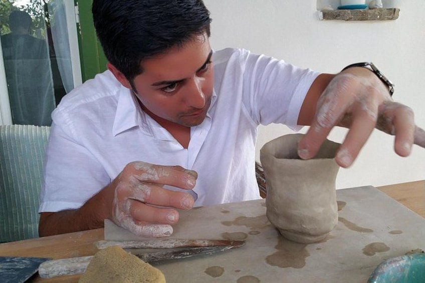A person shaping a clay pot on a table. 4