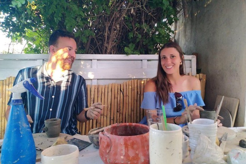 Dos personas sentadas a una mesa con cerámica y material de manualidades. 3