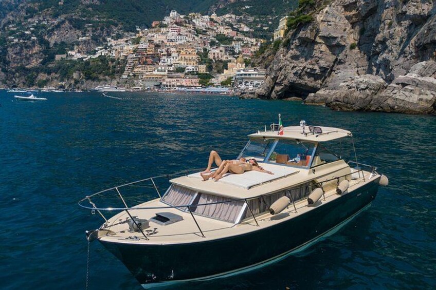 A boat with a person lying on the deck, surrounded by calm water and a coastal town in the background. 5