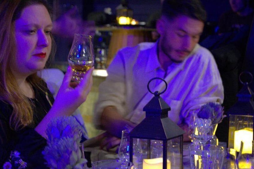 Una persona sosteniendo una copa de vino, una mesa con un farol y una vela. 4