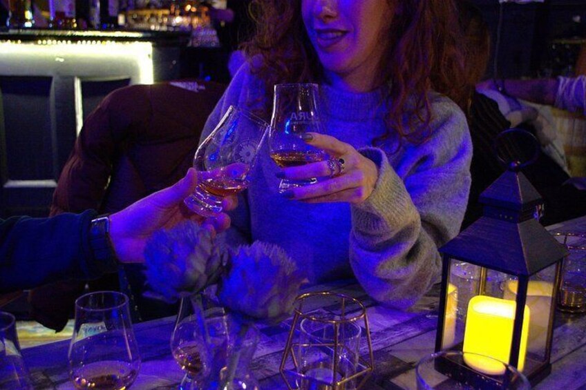 Una persona sosteniendo una copa de vino en un bar con una vela dentro de un farol. 3
