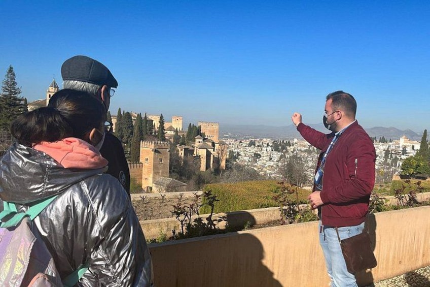 A man gesturing towards a historic cityscape with ancient walls and towers. 5