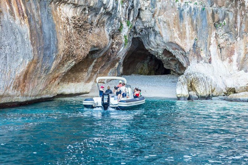 A boat with passengers near a rocky cave entrance. 2