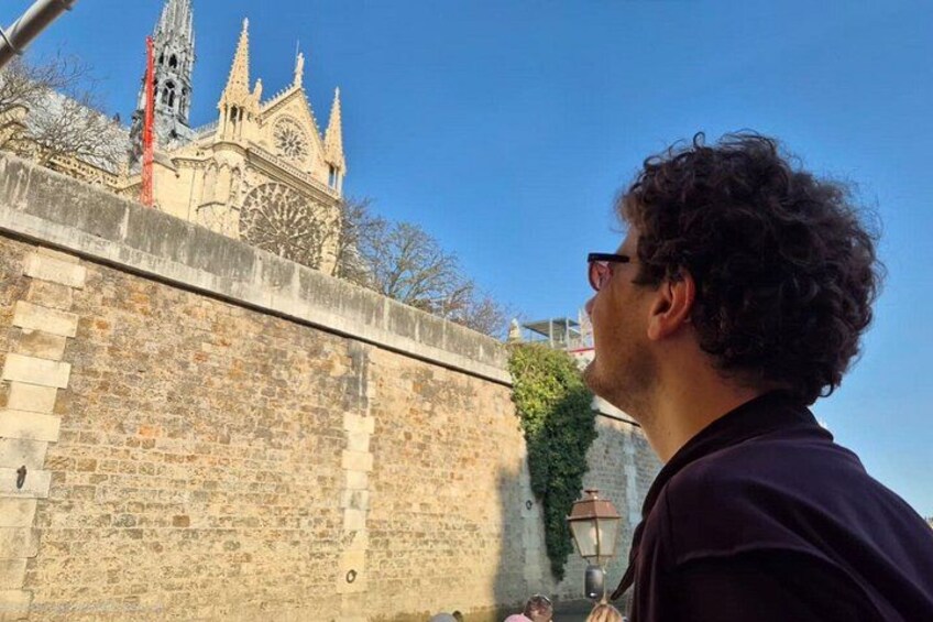 A person standing in front of a historic stone wall with a cathedral in the background. 2