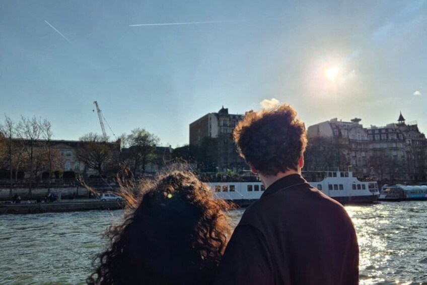 A couple standing by a river with a cityscape in the background. 2