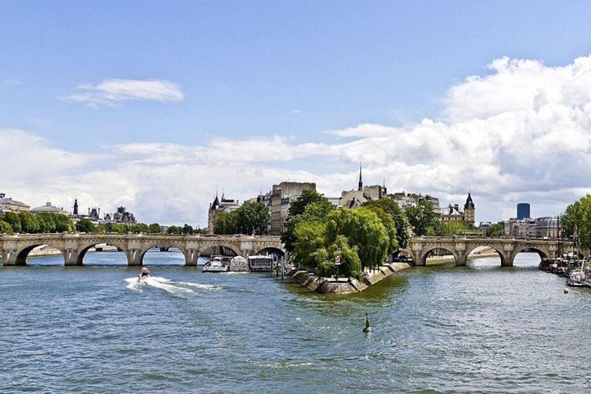 A river with a stone bridge, boats, and a cityscape in the background. 2