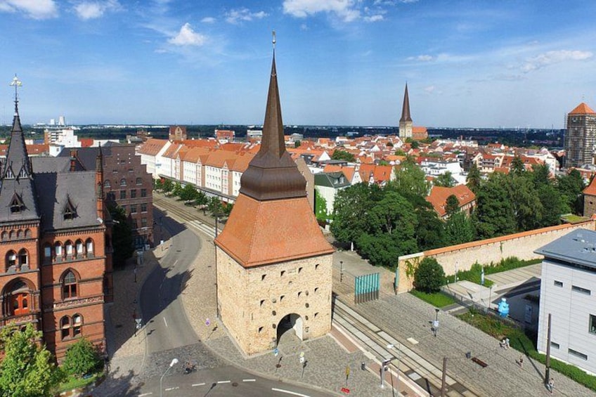 En stadsbild med ett framträdande torn, en kyrktorn och en blandning av historiska och moderna byggnader. 4