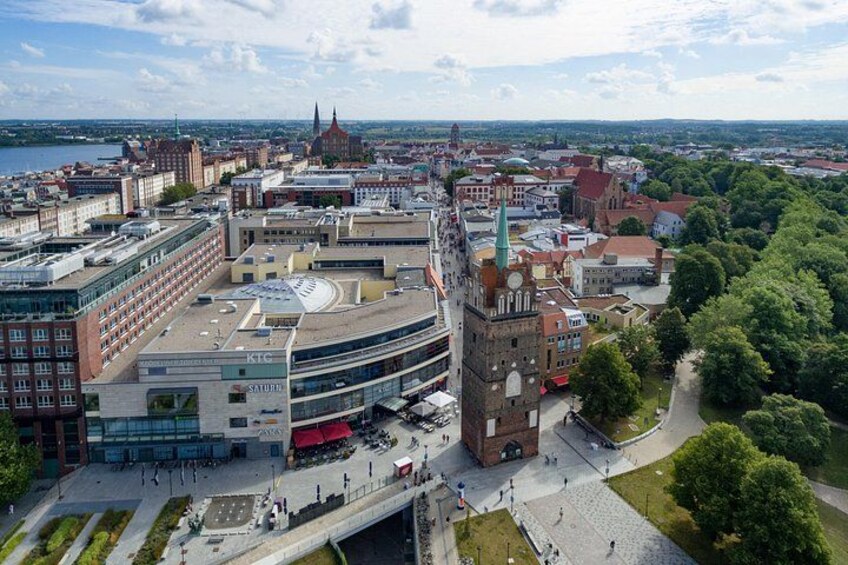 En stadsbild med ett framträdande klocktorn, en modern byggnad med en glasfasad och en flod i bakgrunden. 3
