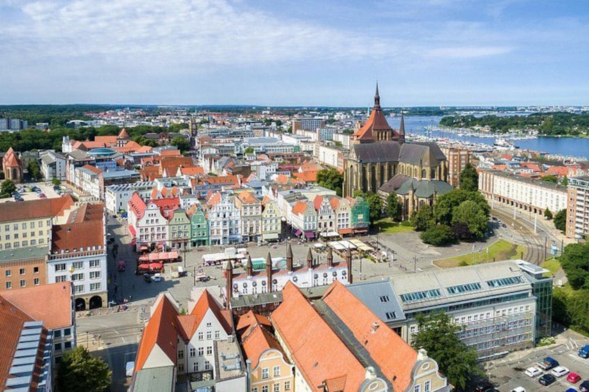 En stadsbild med historiska byggnader, en framträdande kyrka och en hamnfront. 2
