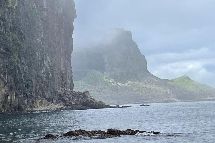 A coastal cliff, rocky shoreline, and calm sea. 4