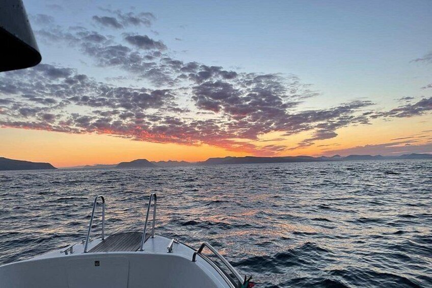 A boat on calm waters during sunset with a clear sky and distant land. 5