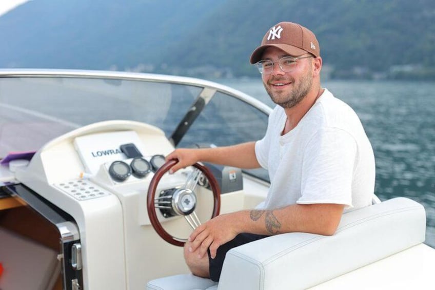 A person steering a boat with a steering wheel and control panel labeled 'LOWRA'. 2