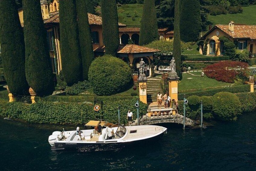 A boat docked at a pier with a statue and a building in the background. 1