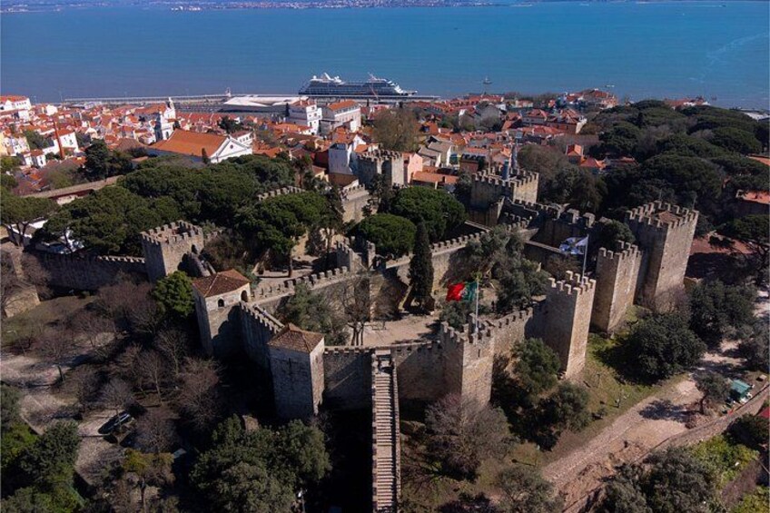 Un castillo histórico rodeado de árboles y un pueblo costero. 3