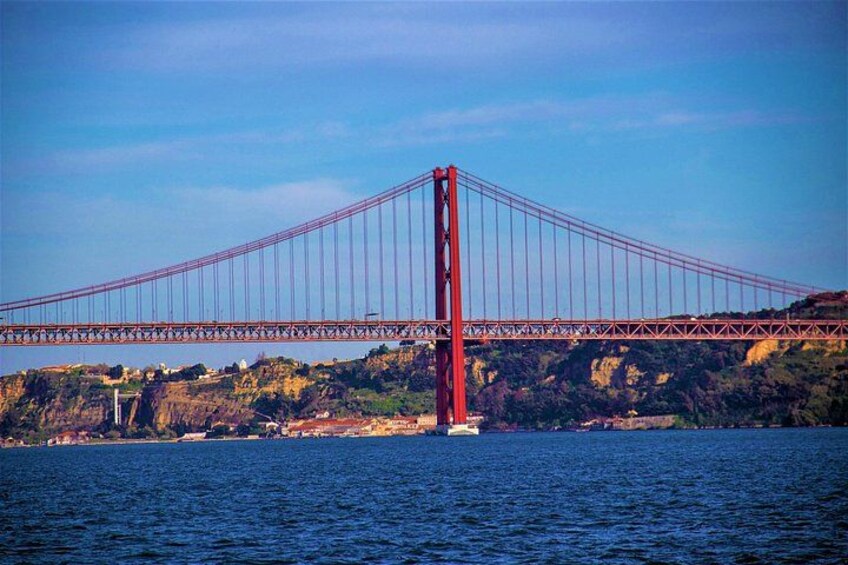 Un puente colgante rojo que cruza un cuerpo de agua, con un paisaje montañoso al fondo. 5