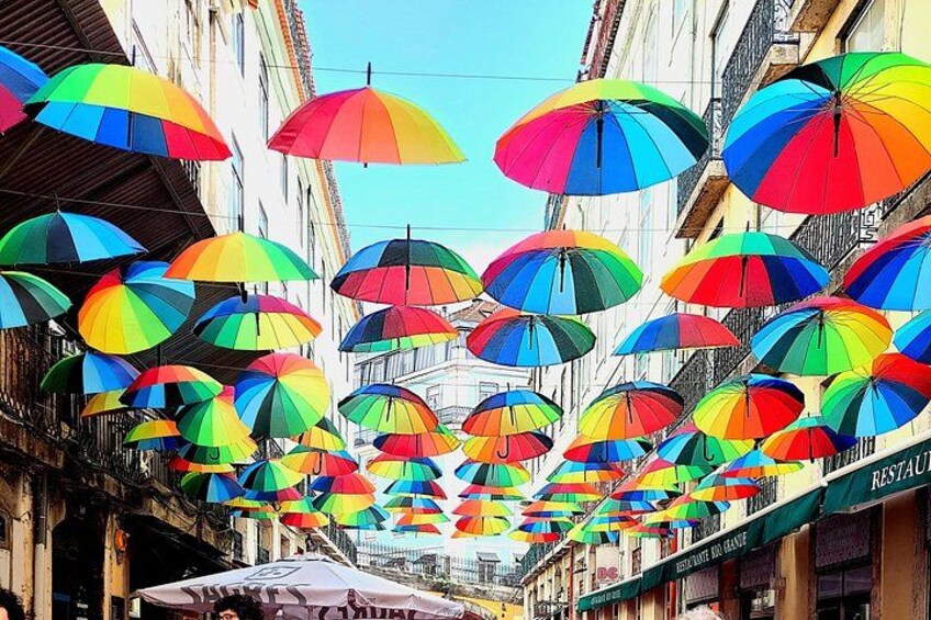 Una calle con sombrillas de colores colgando sobre ella. 1