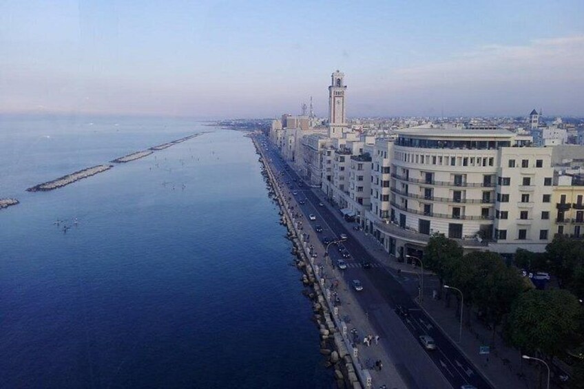 Una città costiera con una lunga passeggiata, un'imponente torre e un mare calmo. 4
