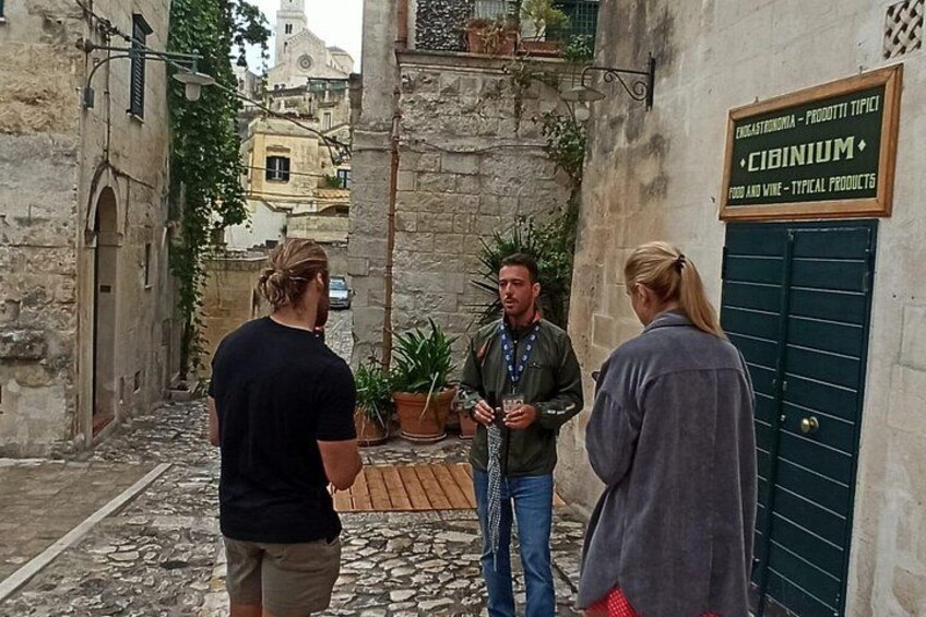 Eine enge Straße mit Steinpflasterung, einem Schild für ein Geschäft vor Ort und Gebäuden mit traditioneller Architektur. 5
