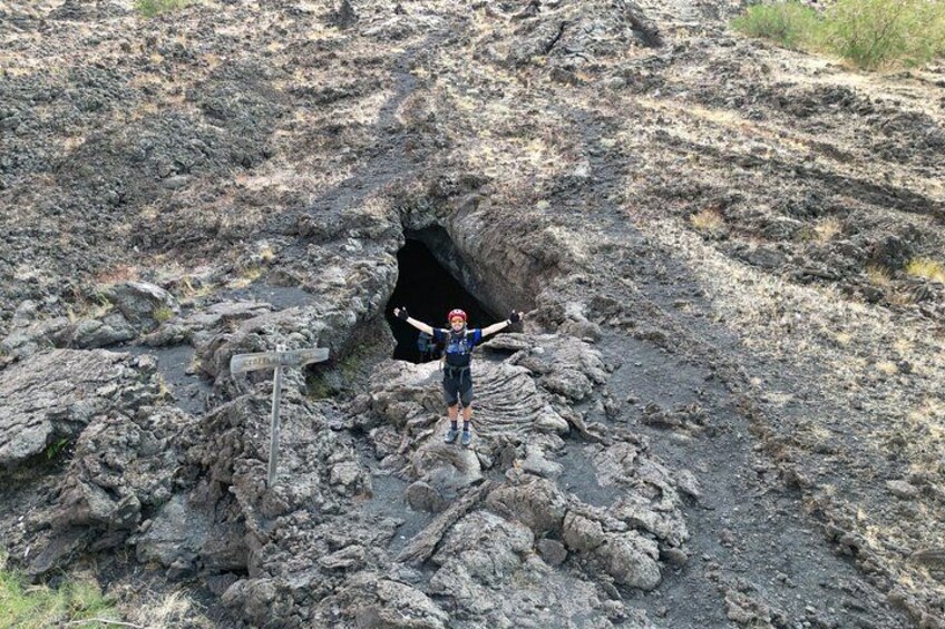 Una persona de pie sobre terreno rocoso con un gran agujero en el suelo. 4