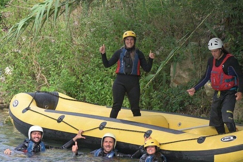 Eine Gruppe von Menschen auf einem gelben Luftmatratzenboot in einem von viel Grün gesäumten Fluss. 2