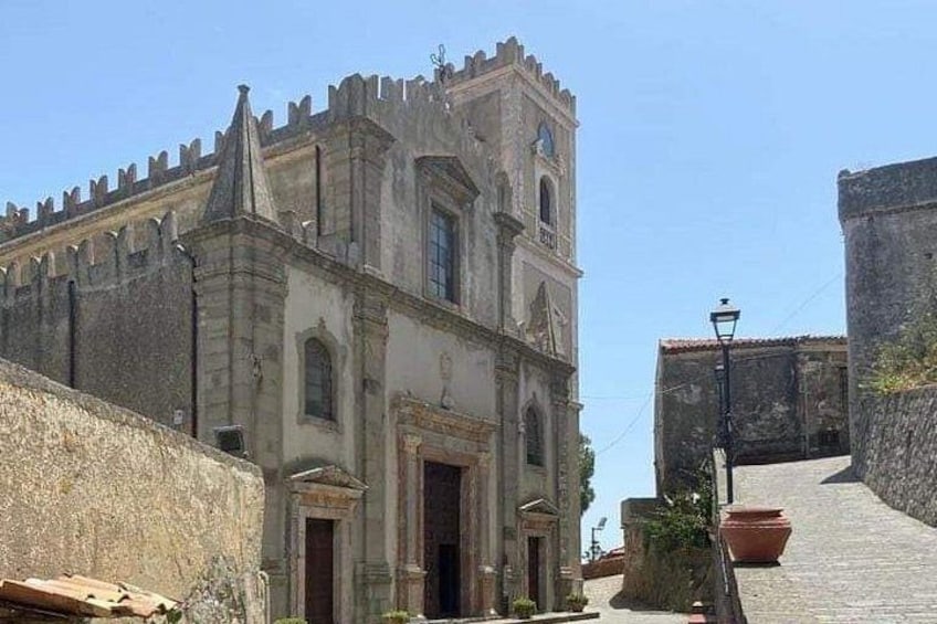 A historic building with a bell tower, a stone wall, and a street lamp. 5