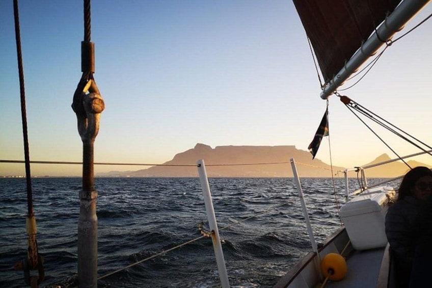 A sailboat on the ocean with a mountainous coastline in the background. 3