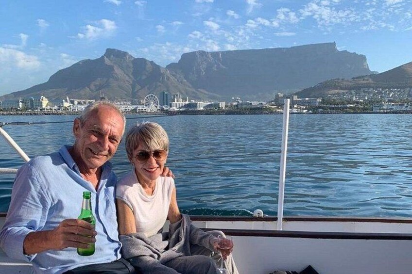 Two people on a boat with a cityscape and mountains in the background. 2