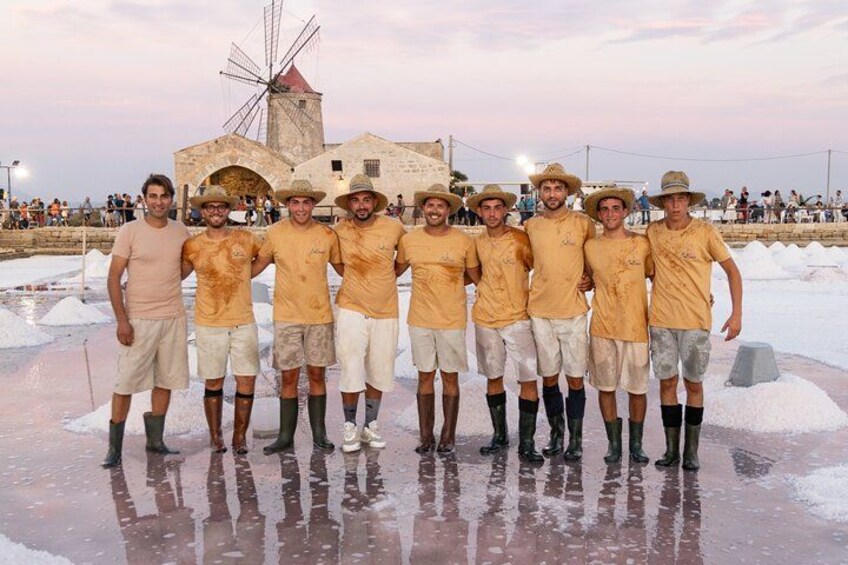 Un grupo de personas sobre una superficie mojada, con un molino de viento y una multitud de fondo. 1