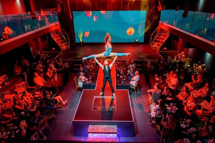 A person performing on a stage with an audience seated around. 4