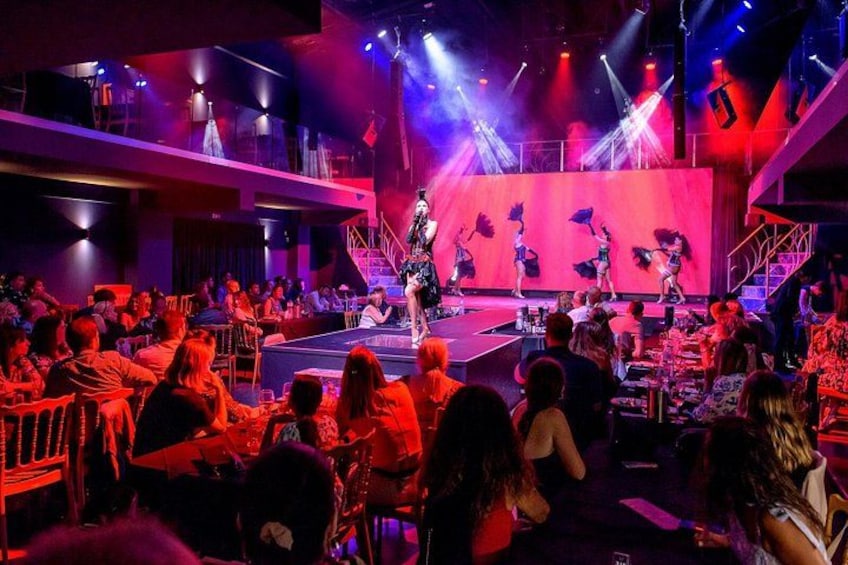 A stage with performers, an audience seated at tables, and a staircase. 5