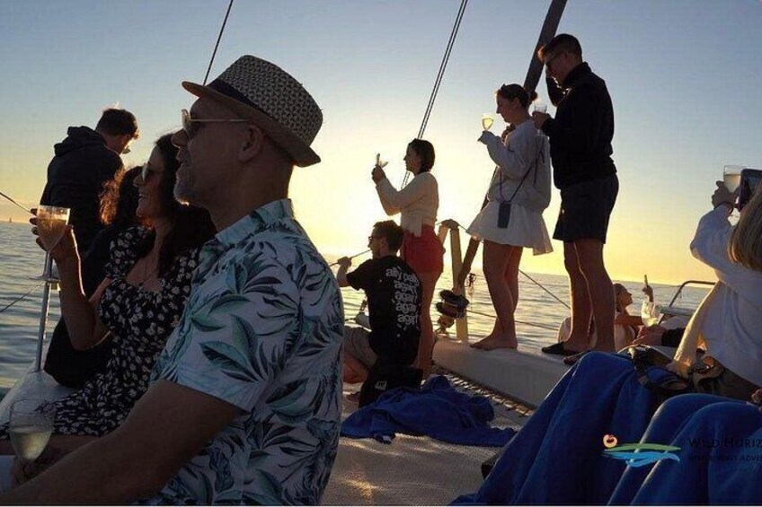 Een groep mensen op een boot bij zonsondergang. 1
