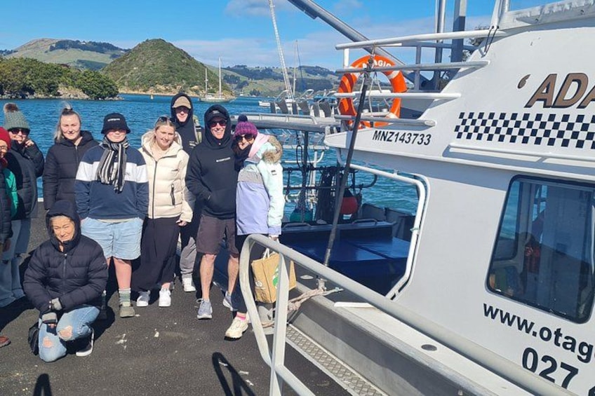A group of people on a boat with a checkered pattern and the text 'ADAG' and 'MNZ143733' on the side. 2