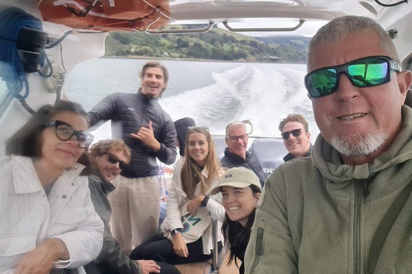 A group of people on a boat with a body of water and greenery in the background. 3