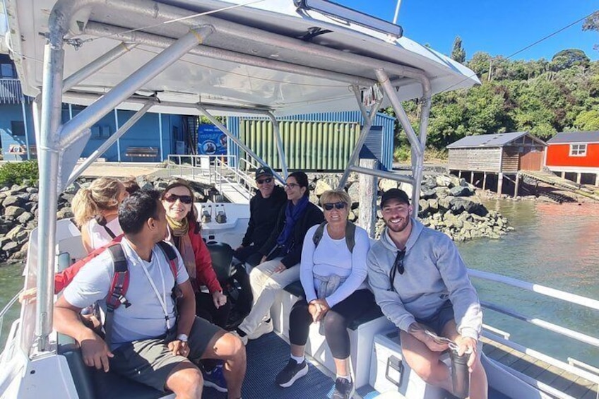 A group of people on a boat with a rocky shoreline and buildings in the background. 5