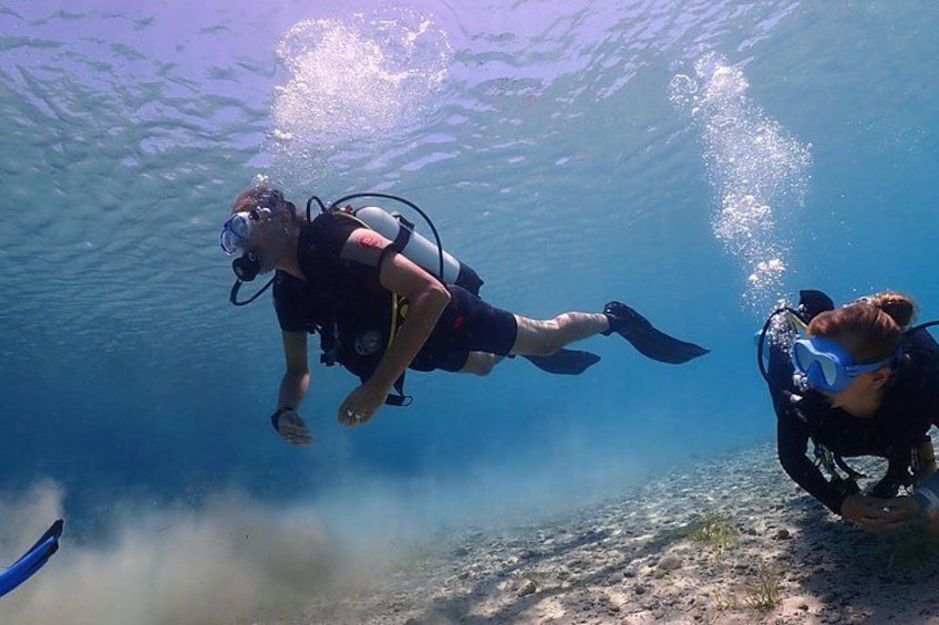 Two scuba divers underwater with fins and tanks. 2