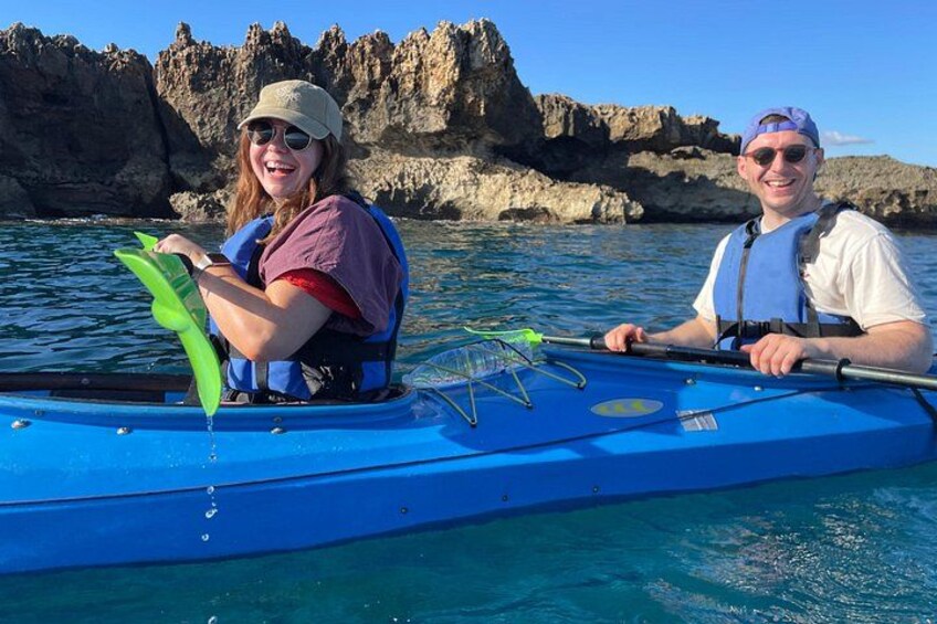 Two people kayaking on a calm body of water with rocky cliffs in the background. 4