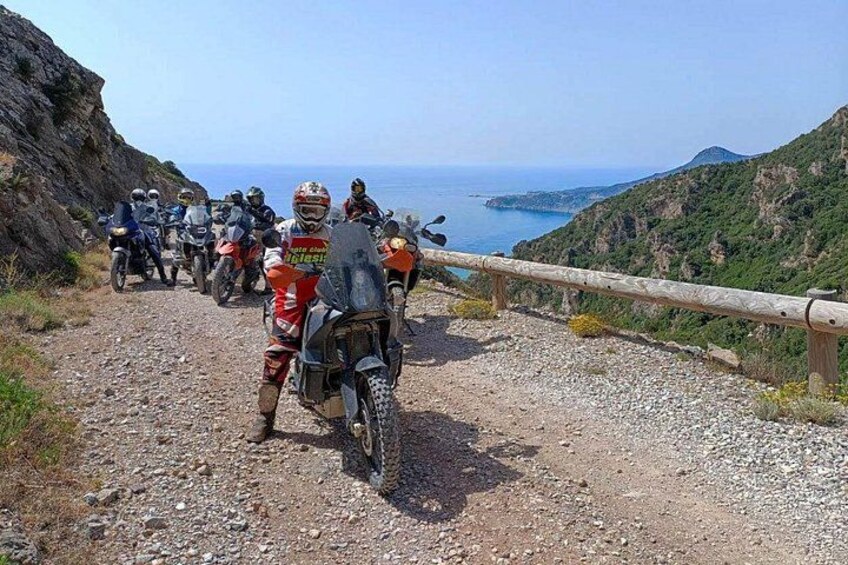 Un grupo de motociclistas en un camino de grava con vistas al mar. 3
