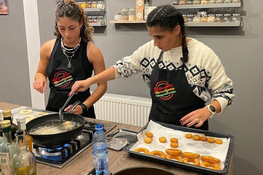 Two people cooking, with one stirring a pan and the other arranging food on a tray. 5