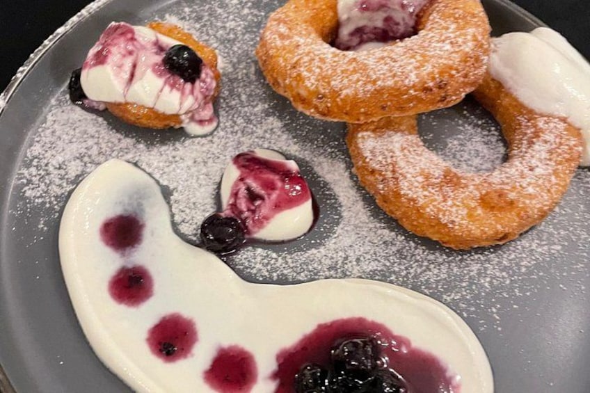 A plate with various pastries, including donuts and a dessert shaped like a heart, all dusted with powdered sugar. 4