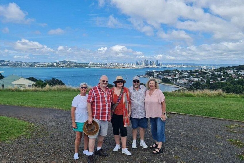 Un grupo de personas de pie en un sendero, con el horizonte de una ciudad y agua al fondo. 5