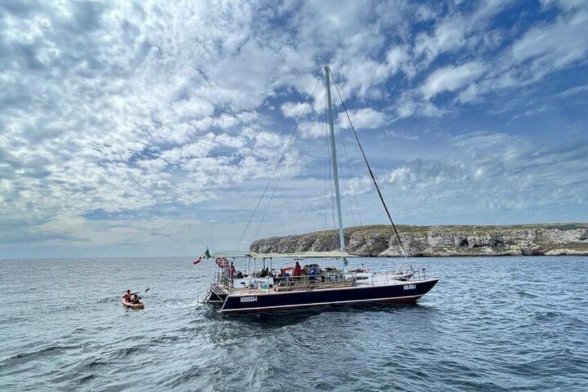 A sailboat on calm waters with a rocky coastline in the background. 2