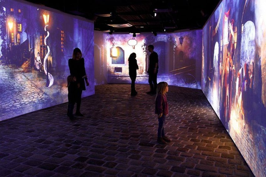 An indoor art gallery with illuminated projections on the walls. 3