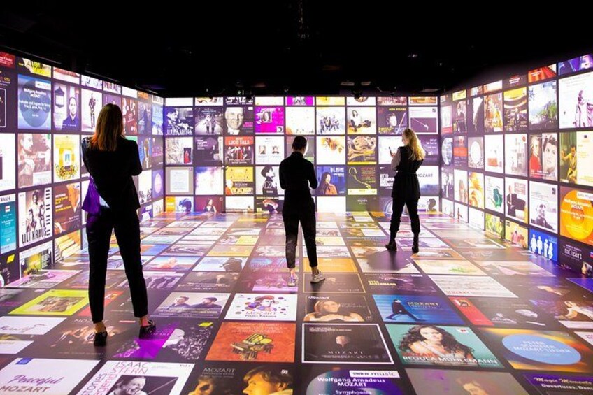A group of people standing in front of a wall displaying various posters. 2
