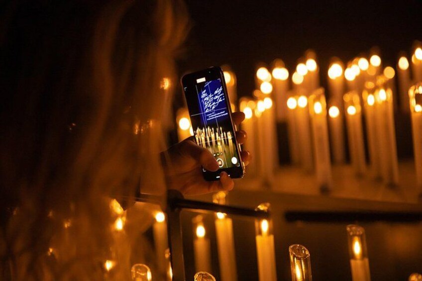 A person holding a smartphone with a lit candle in the background. 5