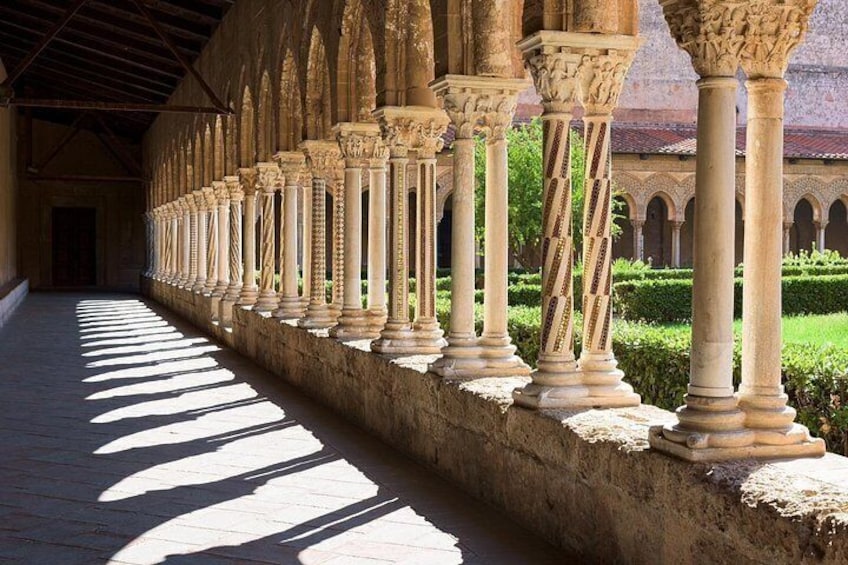 A series of columns in a covered walkway with a patterned floor. 2