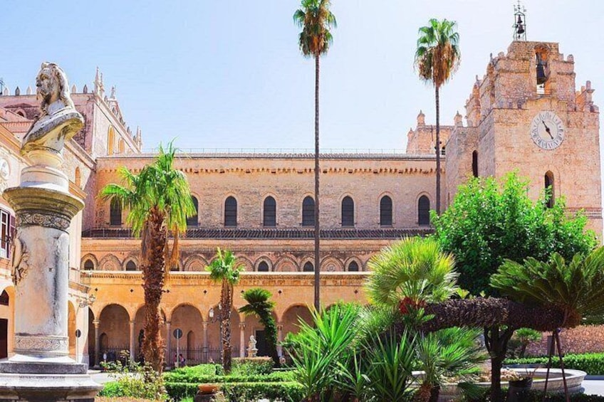 A historic building with a clock tower, palm trees, and a fountain. 3