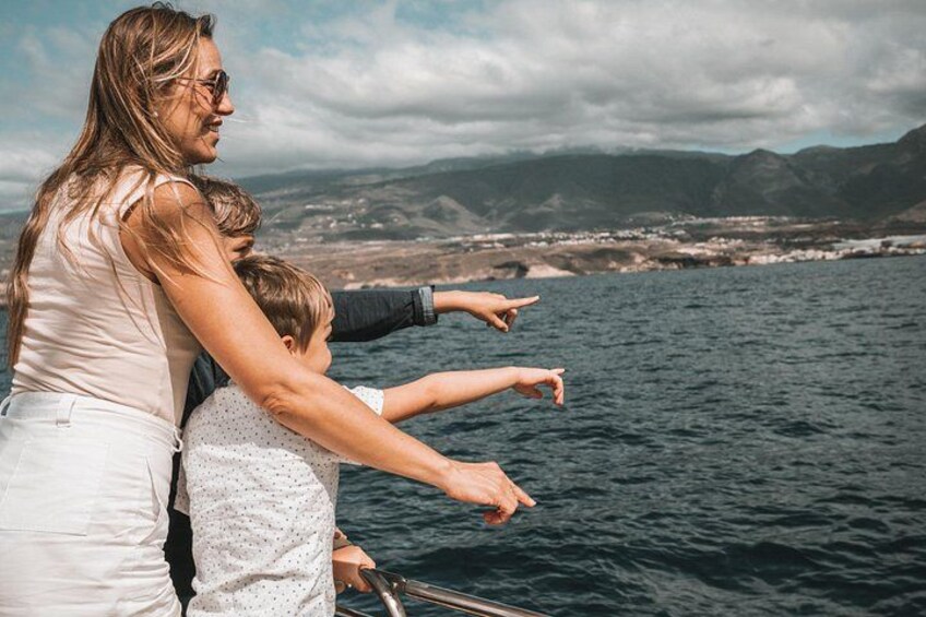 Une femme et un enfant sont à bord d’un bateau et pointent du doigt une côte, avec des montagnes en arrière-plan. 5